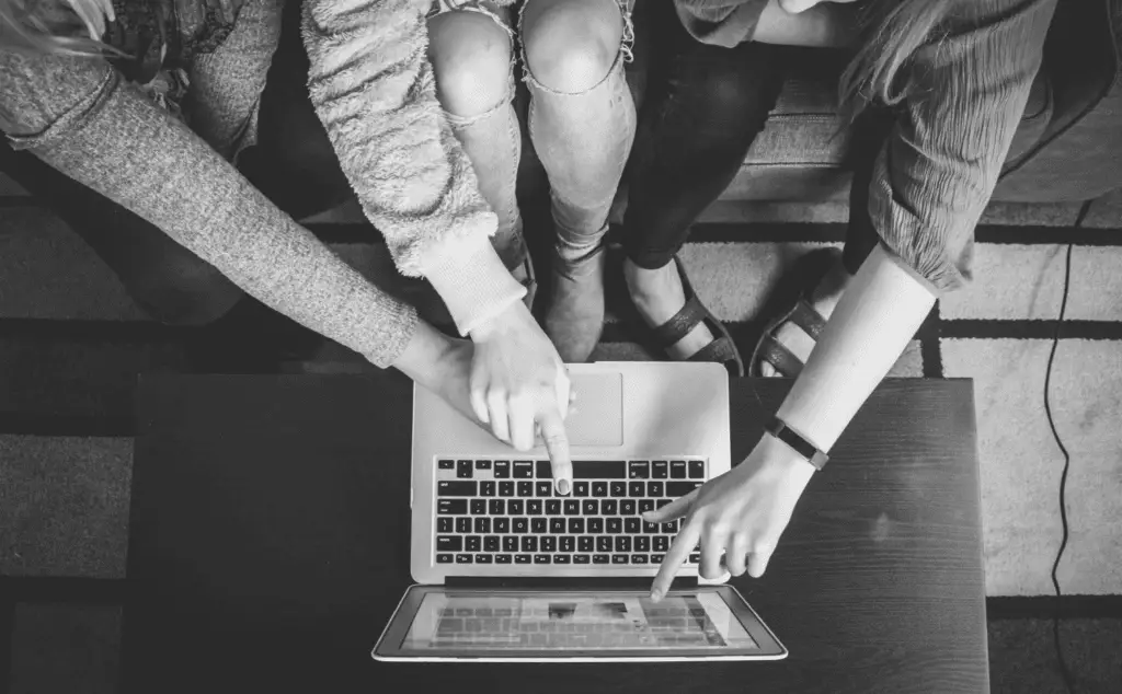 This image of college students pointing at a computer together illustrates the ecommerce angle of our anti-counterfeiting discussion including events like Black Friday.