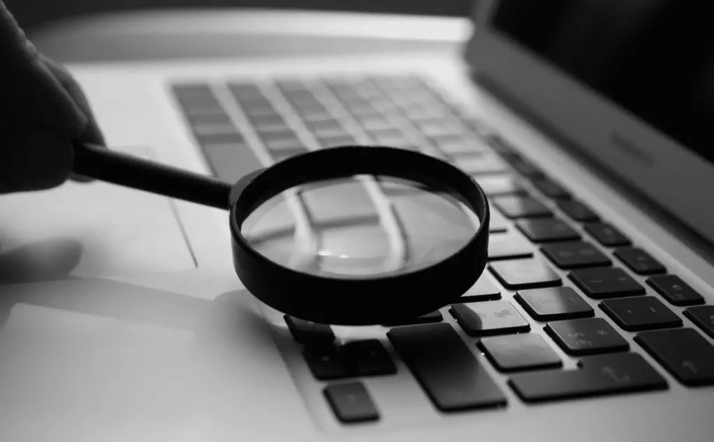 This image of a magnifying glass on a keyboard highlights the investigative element of today's cybersecurity discussion.
