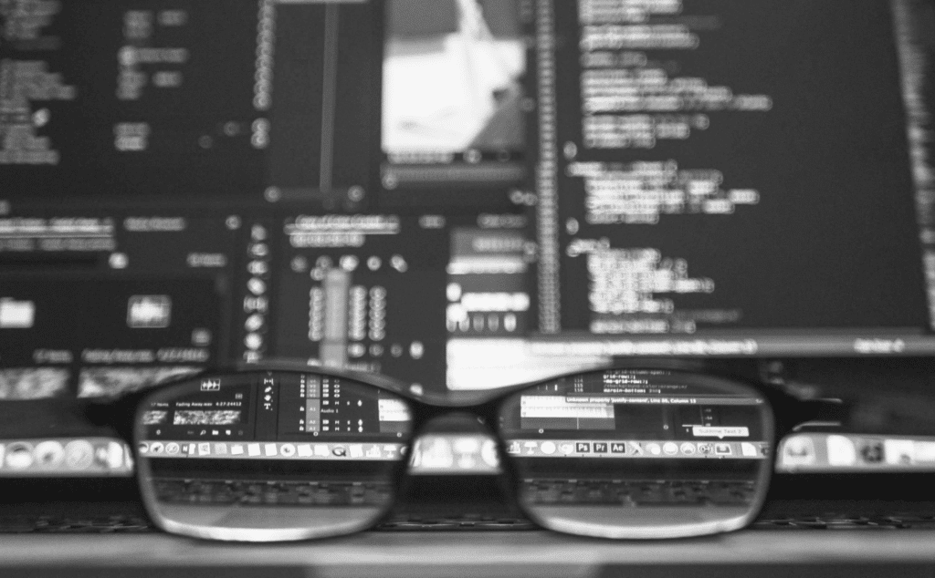 This image of a pair of spectacles in front of a computer screen highlights the importance of monitoring in DNS server security.