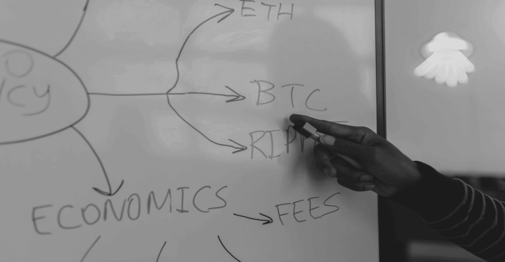 This image of a hand pointing to a whiteboard covered in blockchain terms like ETH, BTC, and ECONOMICS illustrates EBRAND's leadership on this blog's topic, Web3 domains.