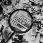 This image of a magnifying glass hovering over cash and goods highlights this post's topic: a fake shop finder.