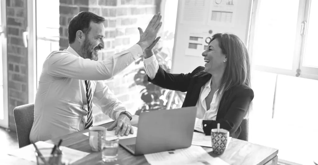 This image of two office workers high-fiving highlights this discussion's topic: the state of scams in Denmark report.