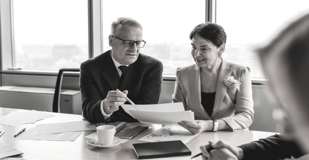 This image of a two smiling colleagues discussion a report demonstrates our discussion topics: Facial recognition and the fight against impersonation scams.