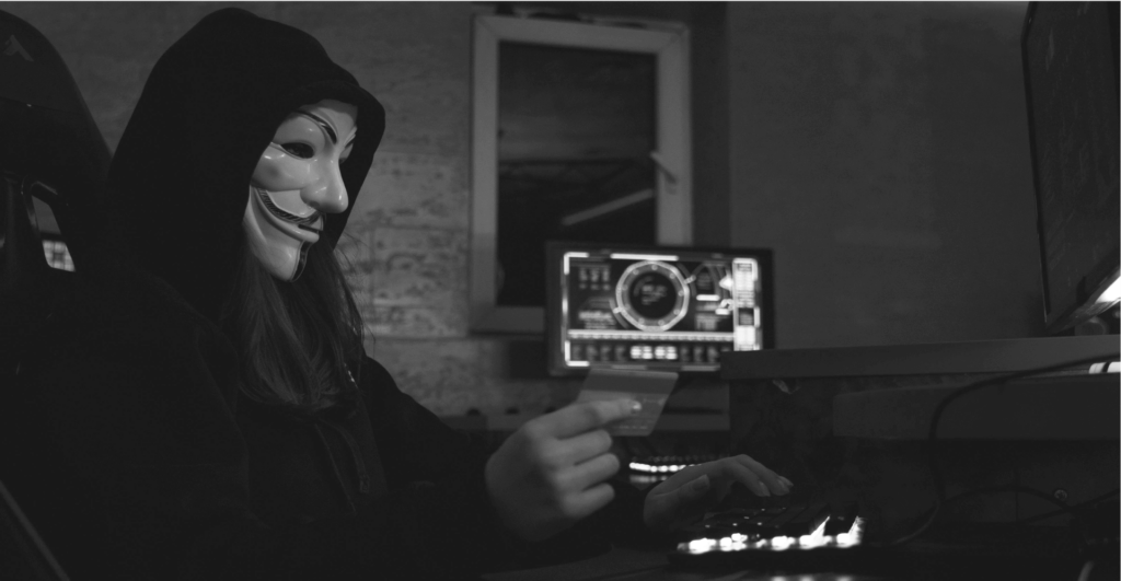 This image of a masked cybercriminal at a computer highlights this post's discussion topics: CDN fake shops, and how to fight back.