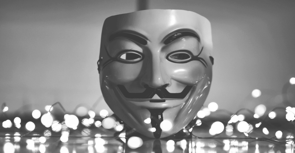 This image of a Guy Fawkes mask in front of ominous glittering lights demonstrates this post's discussion topics: CDN fake shops, and how to fight back.