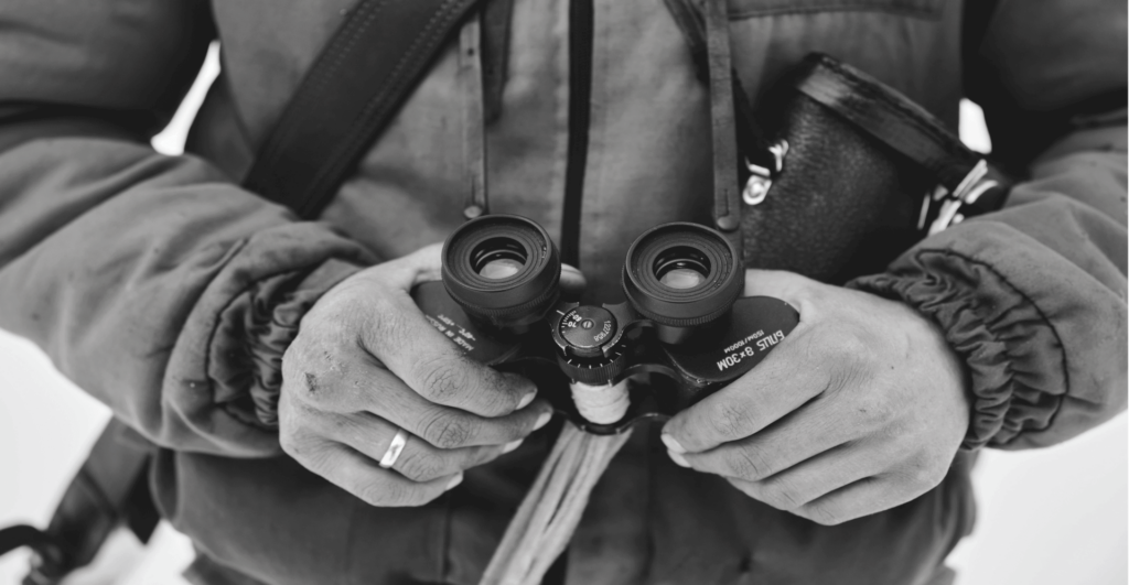 This image of a hunter with binoculars illustrates our discussion topic: Threat hunting, and how it helps brands develop smart protection strategies to fight cyberattackers and protect their businesses.