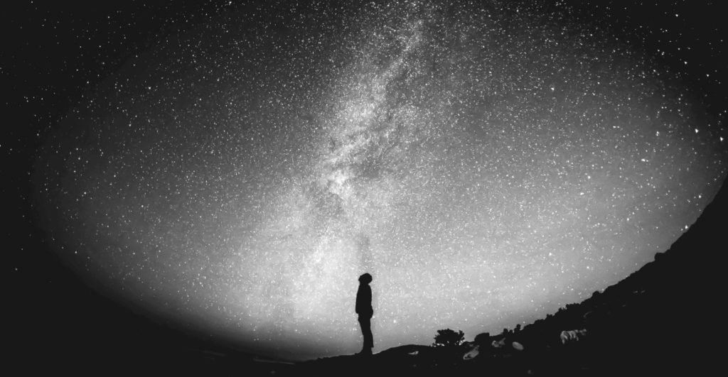 This image of a silhouetted figure looking up at the Milky Way highlights the complexity of domain management, with a specific focus on EBRAND's COSMOS domain platform.