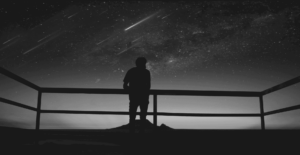 This image of a person looking over a viewpoint bannister at a sky full of stars highlights the complexity of domain management, with a specific focus on EBRAND's COSMOS domain platform.