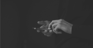 This image of someone on their phone highlights the discussion topic of online banking, and how organizations should chase banking cyberattacker away from their online landscapes with digital risk protection.