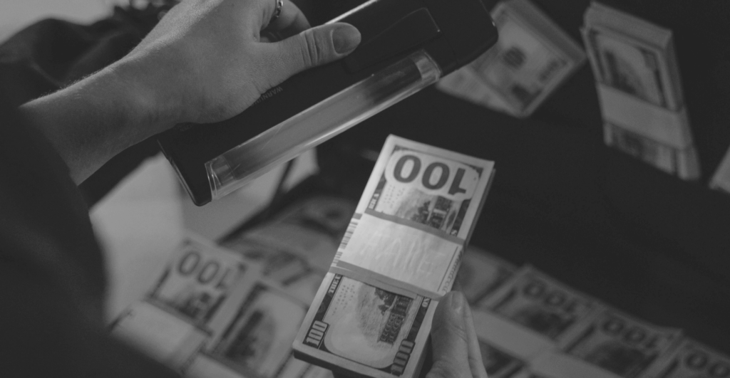 This image of someone scanning a wad of banknotes illustrates our discussion topic: Modern banking scams, and how to tackle them.