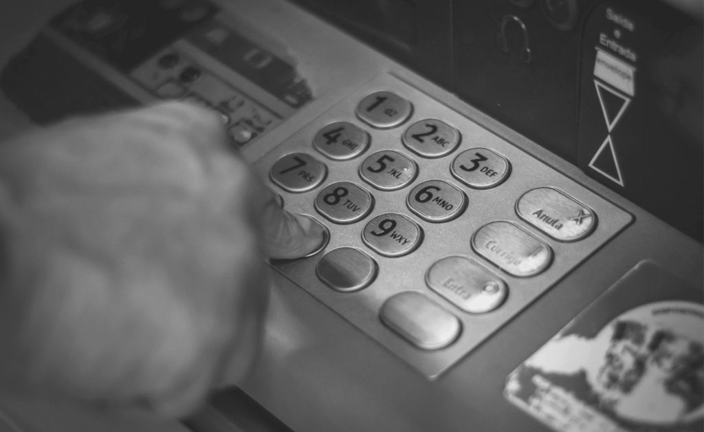 This image of someone entering their PIN at an ATM illustrates our discussion topic: Modern banking scams, and how to tackle them.