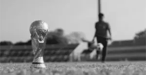 This image of the world cup trophy on a pitch nexxt to a football illustrates our topic about the World Cup, the infringements and online brand issues there, and how to fight back.
