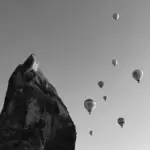 This image of a seven hot air balloons in flight next to a mountain peak illustrates our discussion about launch day scams and frauds, and how to tackle them.