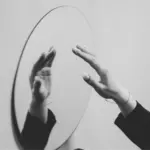 This image of a hand reaching towards its reflection in the mirror illustrates our discussion topic: Dupes, counterfeits, and what brands can do about them.