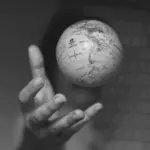 This image of a hand grasping a globe illustrates our discussion topic: DDoS attacks, downtimes, and how the right DNS service helps teams fight back.